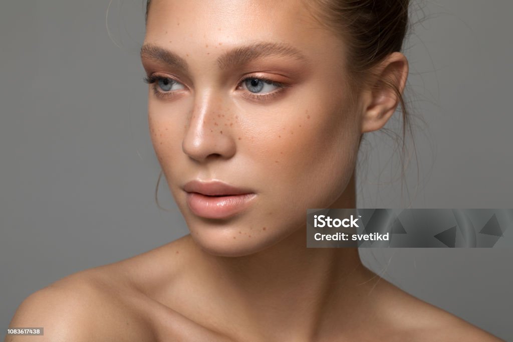 Serene beauty Closeup studio shot of a beautiful young woman with freckles skin posing against a grey background Beauty Stock Photo