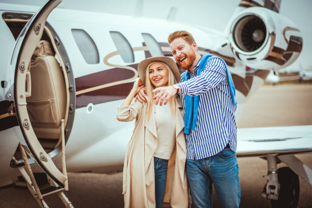 istock Young rich couple hugging next to a private airplane parked on a runway after getting together 1083619772