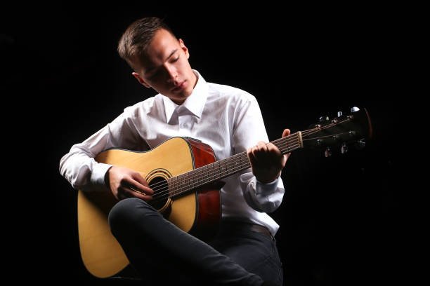 istock Young men playing the guitar with black background 1083625598