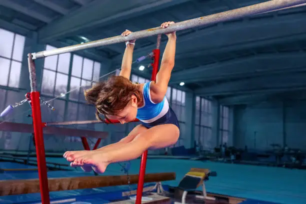 Photo of beautiful girl is engaged in sports gymnastics on a parallel bars