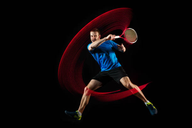 un uomo caucasico che gioca tennista su sfondo nero - tennis men indoors serving foto e immagini stock