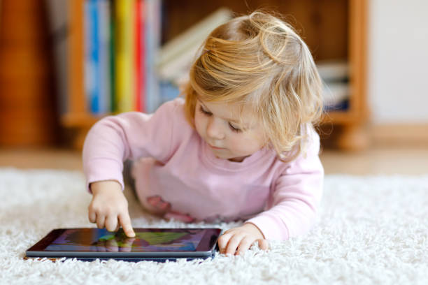 istock Cute little toddler girl playing with tablet pc at home. Healthy baby touching pad with fingers, looking cartoons and having fun with educational games on computer. Early development concept 1083631990
