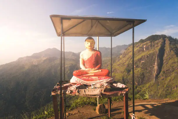 Beautiful view from little Adams peak at Sri Lanka. Fresh nature background. High mountain with trees, blue sky. Buddha statue at sunset.