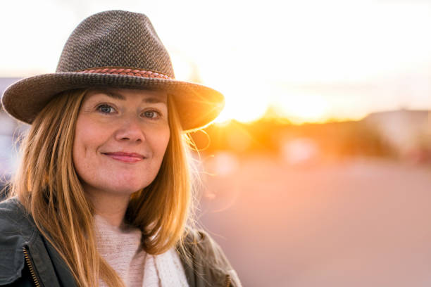 Portrait of confident smiling woman. Close-up of beautiful mature female wearing hat. She is outdoors during sunny day.