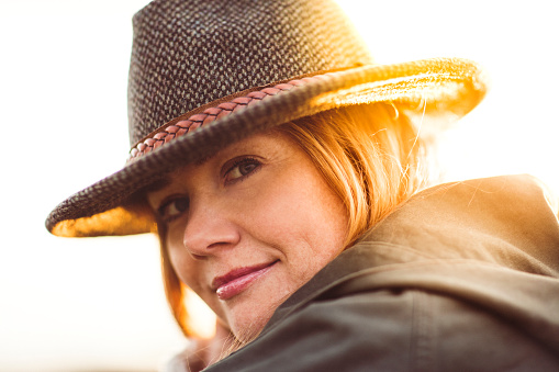 Close-up of confident smiling woman. Portrait of beautiful female wearing hat. She is outdoors during sunny day.