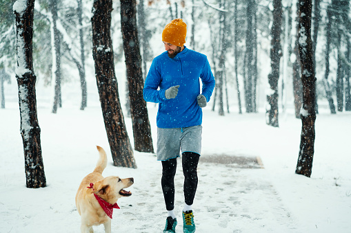 Young man with his dog jogging on winter day