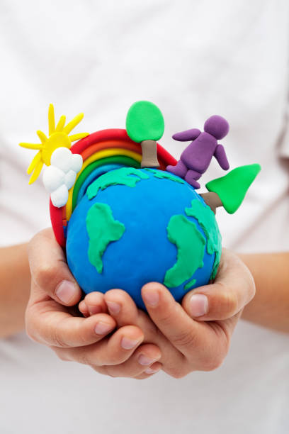 istock Modelling clay earth with rainbow and trees in child hands 1083649384