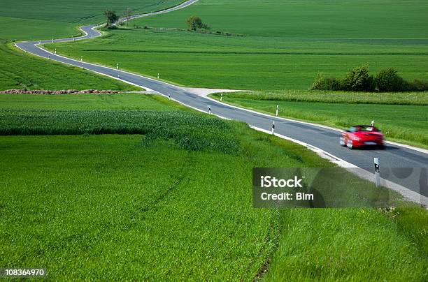 Photo libre de droit de Voiture De Sport Rouge Accélérer Sur Rural Route Sinueuse Au Printemps banque d'images et plus d'images libres de droit de Voiture de sport