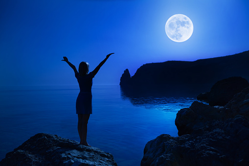 Woman stand with hand up to moon.