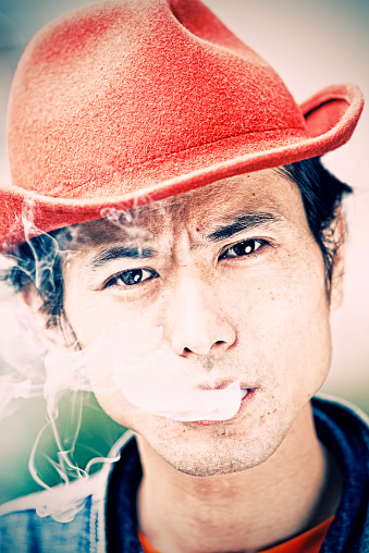 Japanese man with hat enjoying smoking cigarette. Cross processed colors. Taken on iStockalypse Tokyo, Japan, 2010.