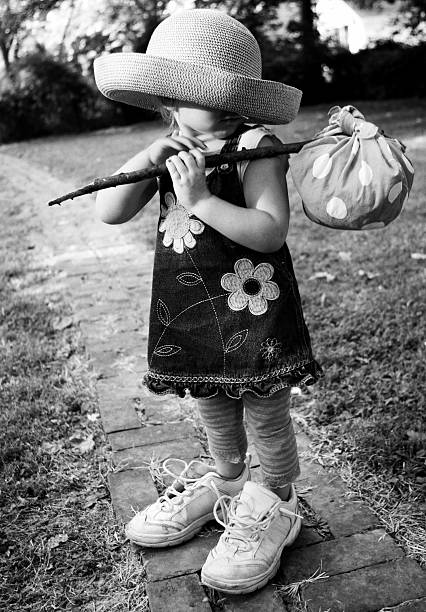 Big Shoe Children: Unrecognizable little girl with hobo luggage stock photo