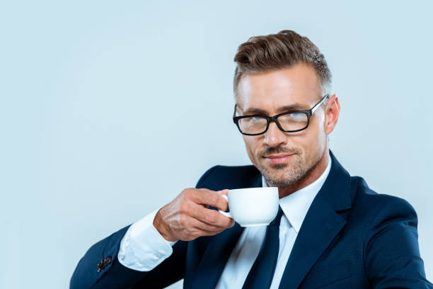 istock handsome businessman drinking coffee and looking at camera isolated on white 1083657582
