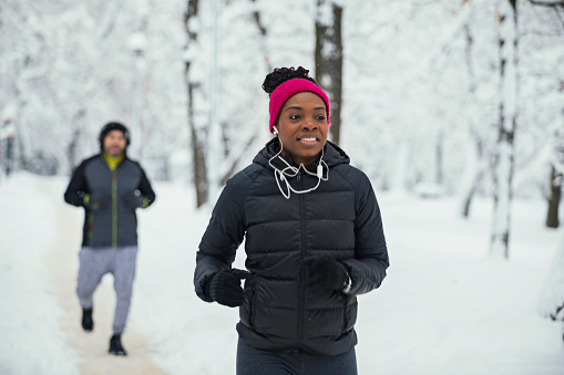 African woman with her friend enjoying in winter jogging