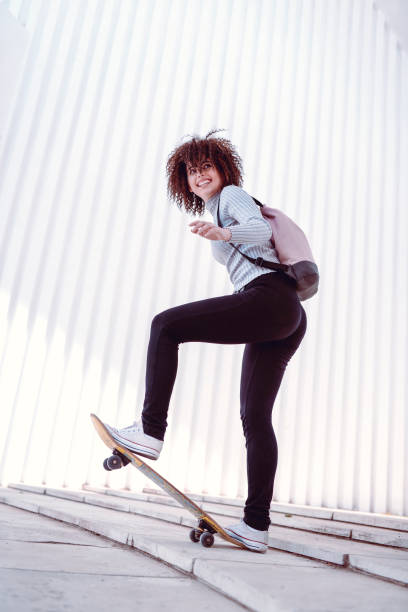 istock Cute Female Skater Posing While Doing Skateboard Trick 1083666334