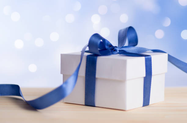 istock One Christmas gift box with blue ribbon bow and bokeh background. 1083666654