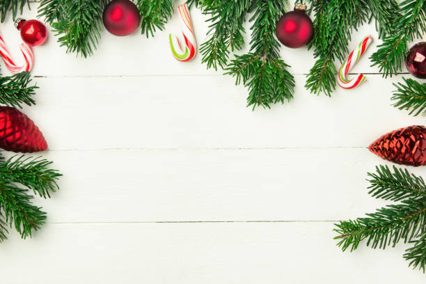istock Fresh fluffy fir tree branches red ornament balls candy canes on white plank wood backdrop. Styled Christmas New Year background greeting card poster banner template 1083668080