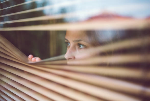 istock Unhappy woman peeks through the window 1083678568