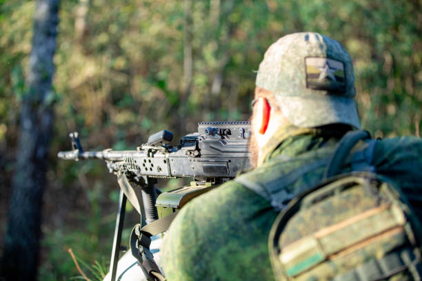 istock Sniper armed with large caliber, sniper rifle, shooting enemy targets on range from shelter, sitting in ambush 1083680558