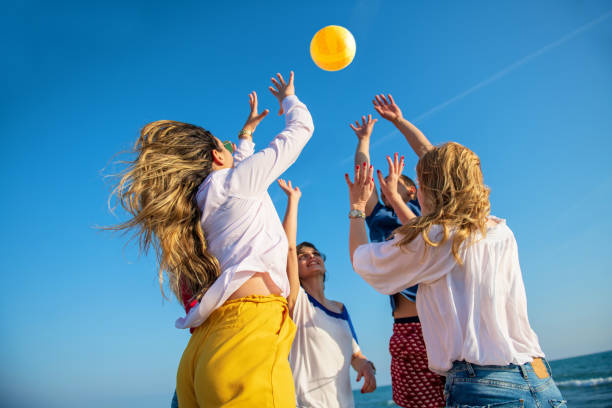 group of young people playing volleyball on the beach - volleyball beach volleyball beach sport imagens e fotografias de stock