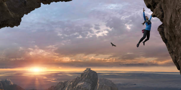 frau free climbing steilen felsen stehen hoch oben bei sonnenaufgang - überhängend stock-fotos und bilder