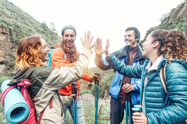 istock Group of friends stacking hands while doing trekking excursion on mountain - Young  tourists walking and exploring the wild nature - Trekker, team, hike and travel people concept 1083684120