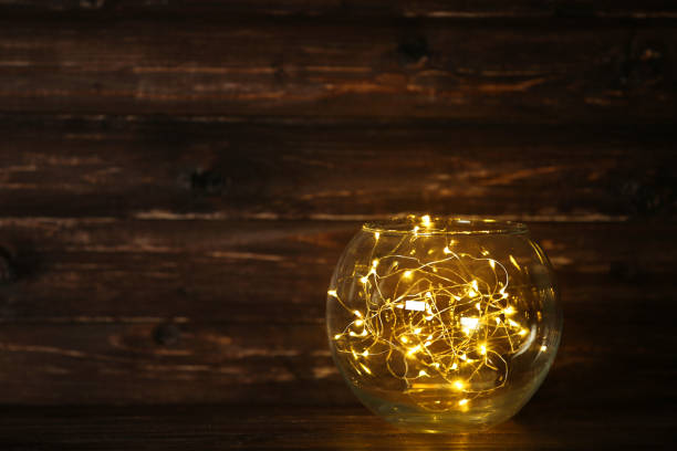 Garland lights in glass bowl on brown background