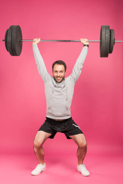 istock strong sportsman training with barbell, isolated on pink 1083686830