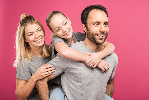 beautiful happy family hugging together, isolated on pink