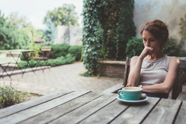 베란다에서 커피를 마시는 우울된 여자 - frustration one person sadness grief 뉴스 사진 이미지