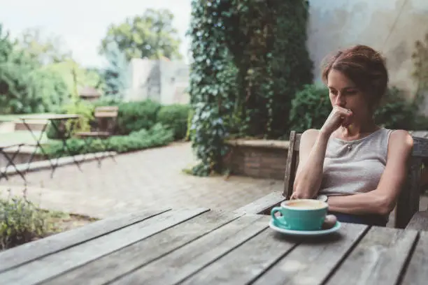 Unhappy woman sitting thoughtfully at the back yard