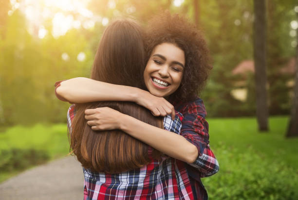 Two happy young girls hug each other outdoors Bff long-awaited meeting. Happy girls hug in park after long separation, copy space friday stock pictures, royalty-free photos & images
