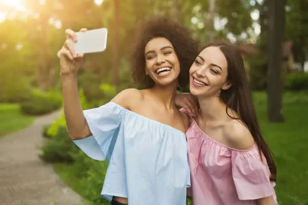 Photo of Two cute young women taking selfie in park