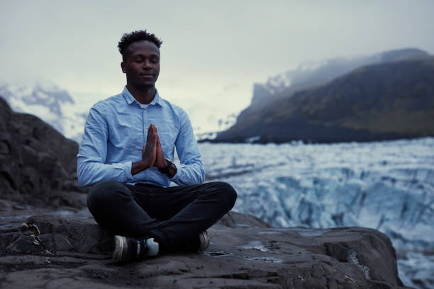 istock African ethnicity man meditating on glacier lagoon 1083706454