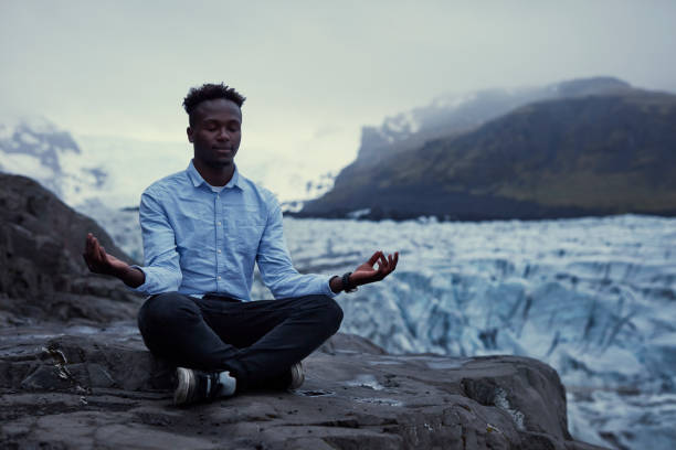 istock African ethnicity man meditating on glacier lagoon 1083706460