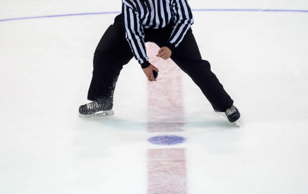 istock Low Section Of Referee Holding Hockey Puck On Ice Rink 1083711042