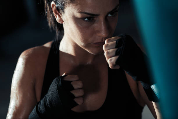 istock Female boxer punching a boxing bag in warehouse. 1083713382