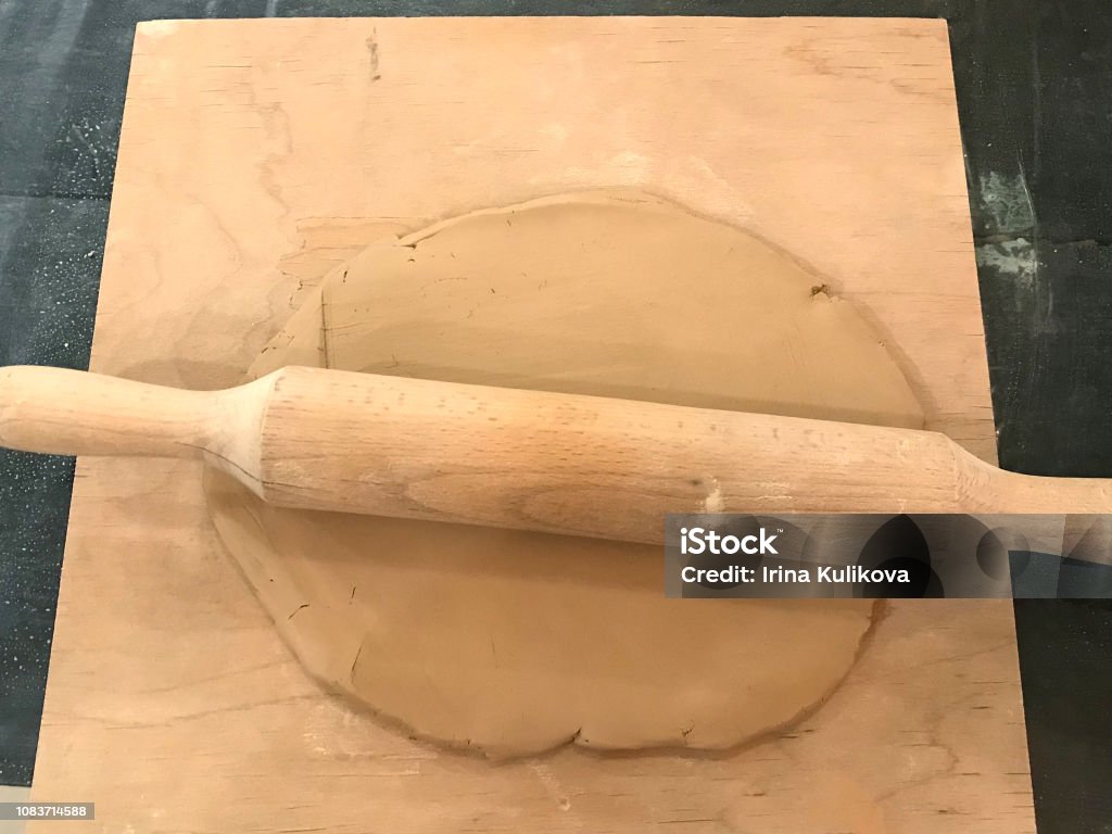 Rolled Piece Of Pottery Clay With A Wooden Rolling Pin On A Board