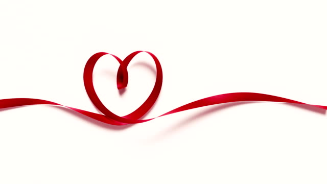 Red ribbon forming a heart shape on white background. 4K resolution. Alpha matte is included at the end of the clip.