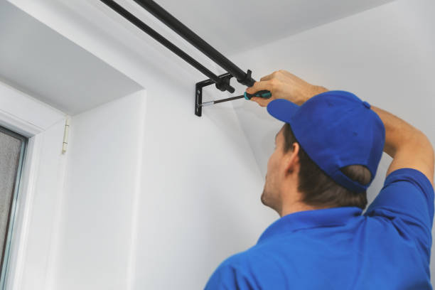 handyman services - worker installing window curtain rod on the wall