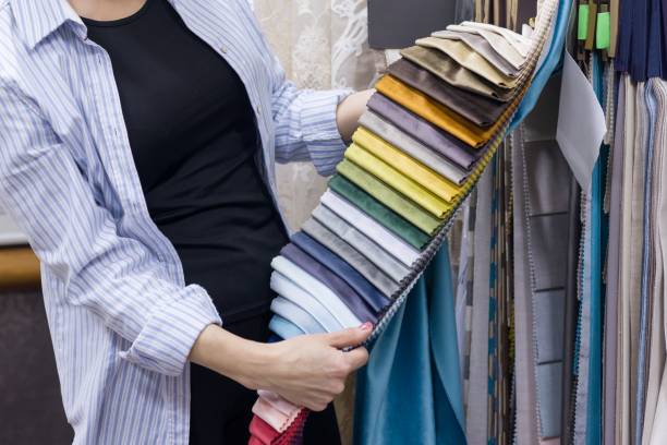 istock Fabrics Store, female looking and touching samples, female designer chooses fabrics for interior decoration 1083721028