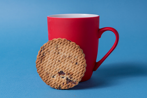 Big red mug and cookie on a blue background.