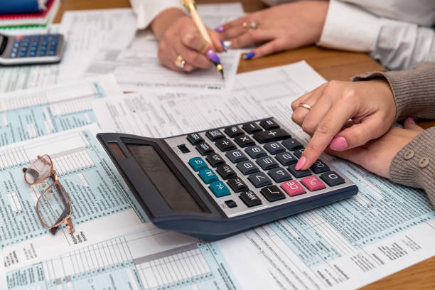 istock Female hands with calculator on 1040 tax form 1083726998