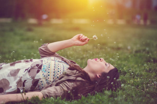 istock Relaxed woman in the park blowing dandelion 1083728218