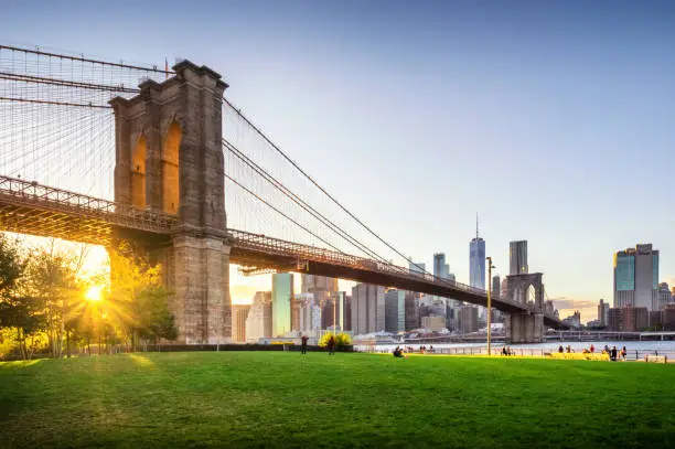 View of Brooklyn Bridge and Lower Manhattan at sunset with sun Flare and a blank space