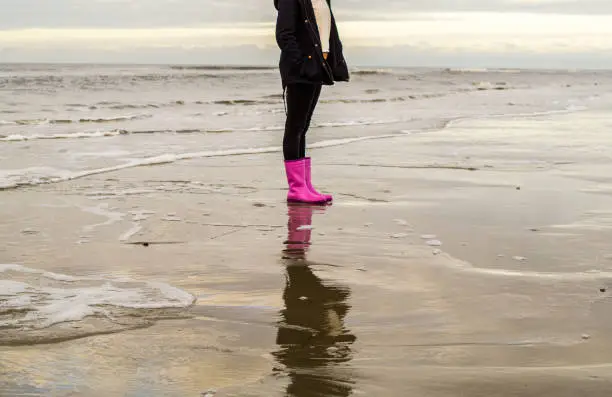 Girl is running with rubber boots at the beach