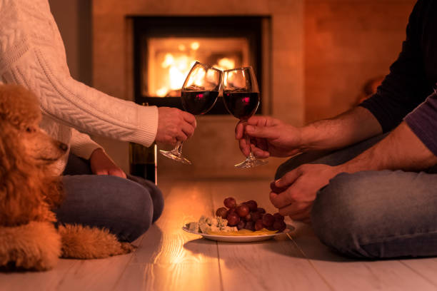 istock Young couple have romantic dinner with wine over fireplace background. 1083736488