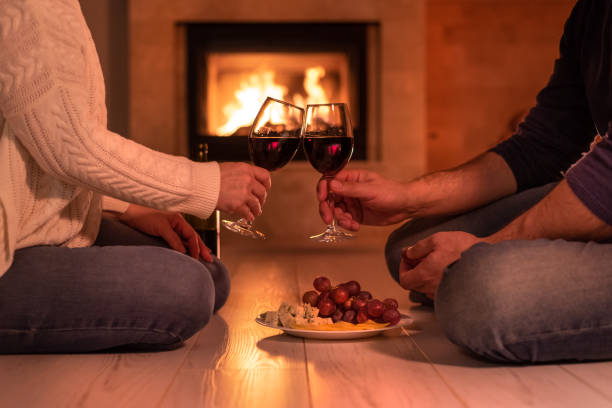 istock Young couple have romantic dinner with wine over fireplace background. 1083736504