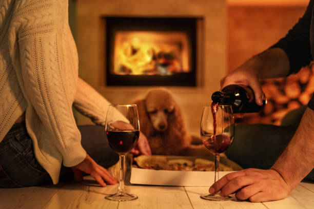 istock Young couple have romantic dinner with pizza and wine over fireplace background. 1083736534