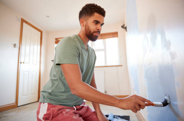 istock Man Decorating Room In New Home Painting Wall 1083738088