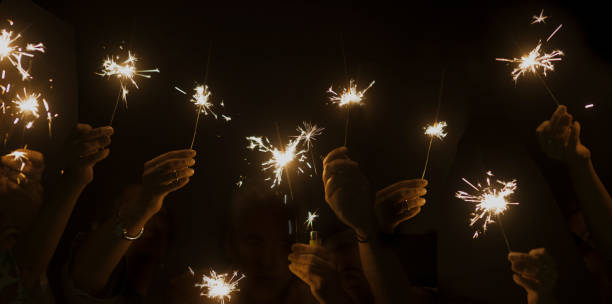 istock dark night celebrate concept with lot of hands taking and using light sparkles fire together. have fun for new year eve or party. companionship and friendship during celebration. happy lifestyle 1083743622